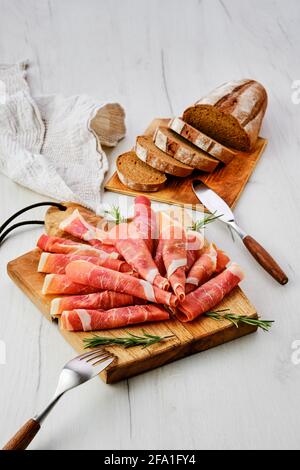 Gerollte Scheiben von Jamon auf Holz Schneidebrett Stockfoto