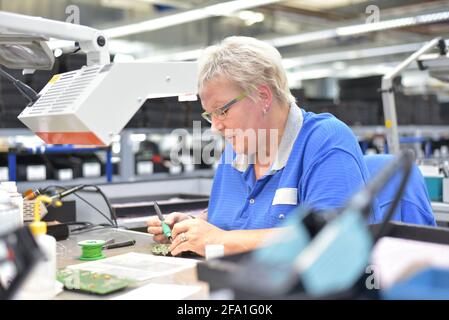 Freundliche Frau in einem mikroelektronikfertigung Factory-Komponenten Montage und Löten arbeiten Stockfoto