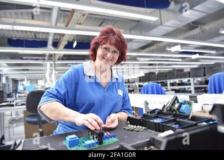 Freundliche Frau in einem mikroelektronikfertigung Factory-Komponenten Montage und Löten arbeiten Stockfoto