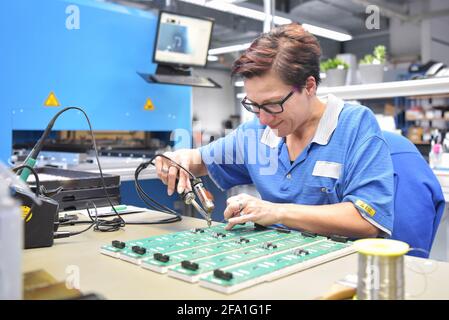 Freundliche Frau in einem mikroelektronikfertigung Factory-Komponenten Montage und Löten arbeiten Stockfoto