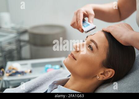 Spa-Klientin, die ihre Poren mit einem Ultraschallspatel reinigen ließ Stockfoto