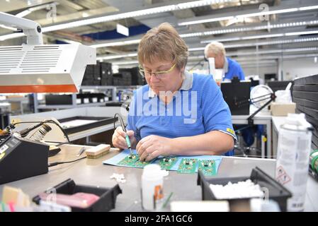 Freundliche Frau in einem mikroelektronikfertigung Factory-Komponenten Montage und Löten arbeiten Stockfoto