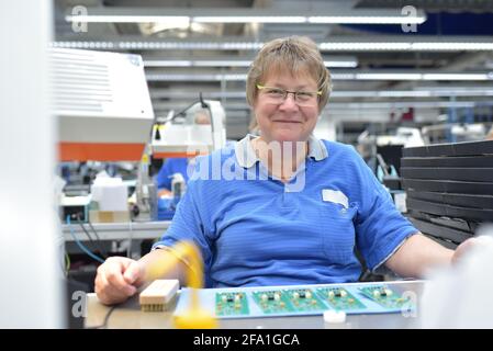 Freundliche Frau in einem mikroelektronikfertigung Factory-Komponenten Montage und Löten arbeiten Stockfoto