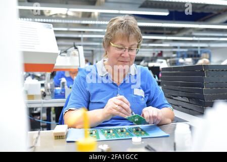 Freundliche Frau in einem mikroelektronikfertigung Factory-Komponenten Montage und Löten arbeiten Stockfoto