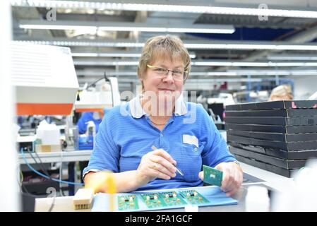 Freundliche Frau in einem mikroelektronikfertigung Factory-Komponenten Montage und Löten arbeiten Stockfoto