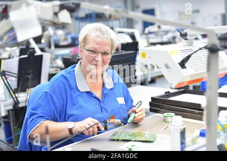 Freundliche Frau in einem mikroelektronikfertigung Factory-Komponenten Montage und Löten arbeiten Stockfoto