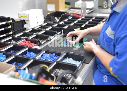 Freundliche Frau in einem mikroelektronikfertigung Factory-Komponenten Montage und Löten arbeiten Stockfoto