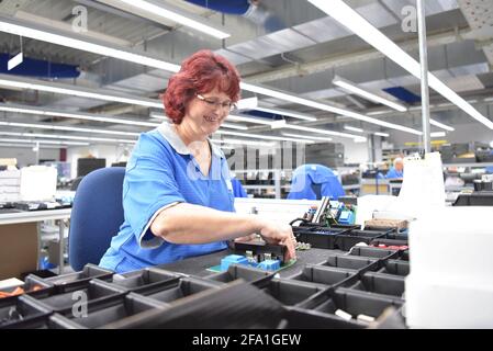 Freundliche Frau in einem mikroelektronikfertigung Factory-Komponenten Montage und Löten arbeiten Stockfoto