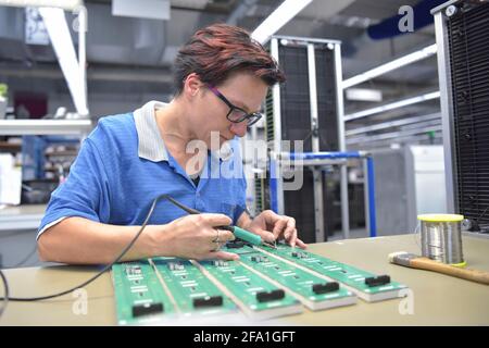 Freundliche Frau in einem mikroelektronikfertigung Factory-Komponenten Montage und Löten arbeiten Stockfoto