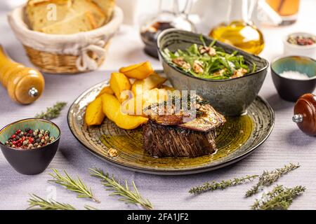 Steak mit gegrillter Entenleber serviert mit Kartoffelkeilen und Aragula auf dem Restauranttisch Stockfoto