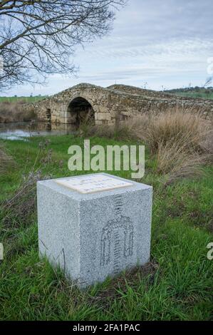 Mittelalterliche Brücke von Santiago de Bencaliz in der Nähe des Dorfes Aldea del Cano, Caceres, Spanien. Via de la Plata Way oder Silver Route Cube Schild Stockfoto