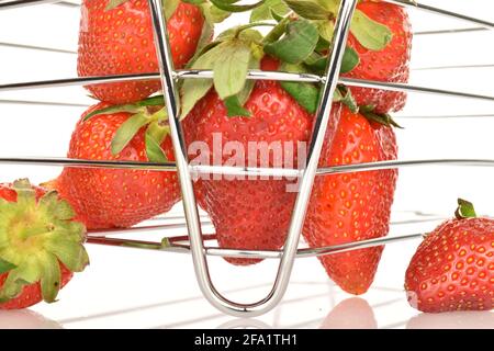 Mehrere Erdbeeren mit Diät, in einem Korbkorb aus Metalldraht, auf weißem Hintergrund. Stockfoto