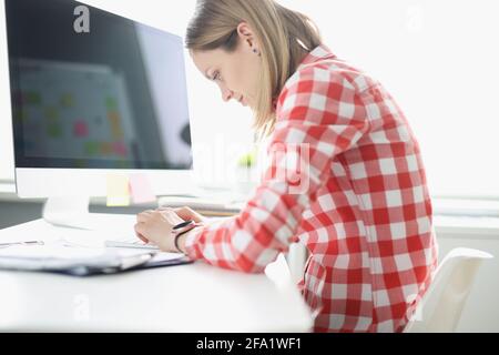 Eine gebeugte Frau, die am Tisch auf der Computertastatur tippt Stockfoto