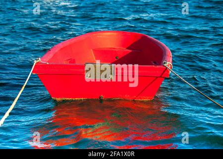 Kleine Beiboot. Isoliert. Rotes Schlauchboot, das in der Marina festgemacht ist. Stockbild. Stockfoto