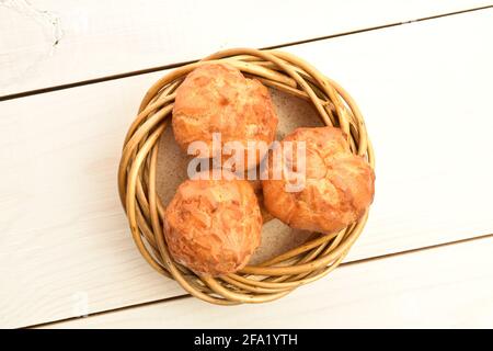 Drei frisch duftende Chouquettes mit Weinkranz, Nahaufnahme, auf einem weißen Holztisch, Draufsicht. Stockfoto