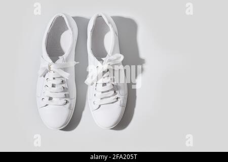 Weiße Gummischuhe auf grauem Hintergrund mit Kopierraum. Wasch- und Reinigungskonzept. Regelmäßige Pflege von Schuhen. Draufsicht. Stockfoto