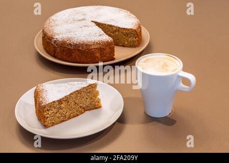 Eine Tasse frischen Cappuccino und ein Stück Kuchen Aus Mandeln und trockenem Brot (Antica torta alle Mandorle e pane) Stockfoto