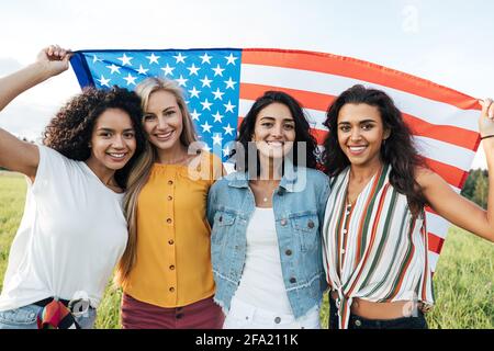 Gruppe von multiethnischen Frauen mit einer US-Flagge. Freundinnen feiern den Tag der Unabhängigkeit. Stockfoto