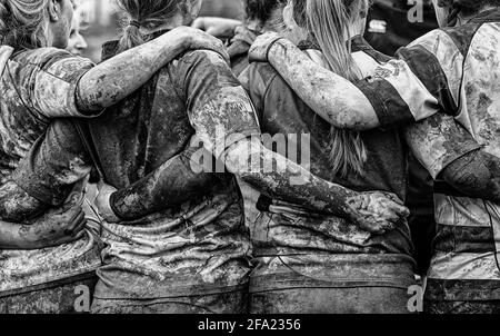 Rugby-Spielerin mit schlammigen Armen und Körpern in Rugby-Huddle Stockfoto