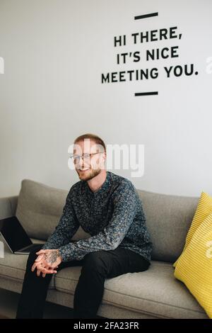Business Executive zum Entspannen und Sitzen auf dem Sofa. Selbstbewusster Mann, der auf dem Sofa in der Lobby sitzt. Stockfoto