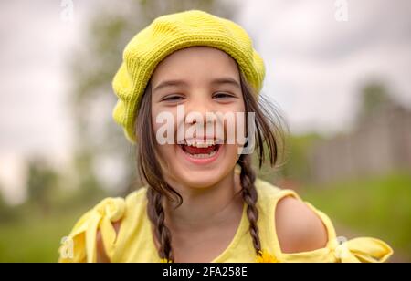 Außenaufnahme Porträt eines kleinen entzückenden glücklichen Mädchen in Eine gelb gestrickte Baskenmütze Stockfoto