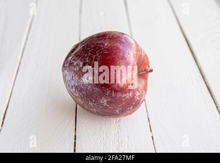 Roter Apfel mit weißer Schicht Schutzwachs, der sich nach dem Waschen des Apfels zu Hause teilweise auflöst. Vor dem Verkauf im Geschäft, sie wenden Wachs. Stockfoto