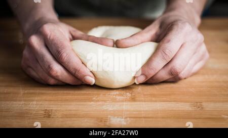 Frau knetet Brot auf einem hölzernen Schneidebrett Stockfoto