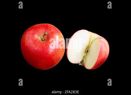 Frische reife rote Äpfel ganze Früchte mit einem halben Schnitt Auf schwarzem Hintergrund Stockfoto