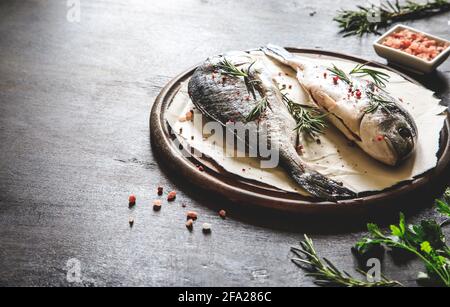 Frischer, roher dorado-Fisch auf einem Holzbrett mit rosafarbenem himalaya-Salz, rosa Pfefferkörnern und Rosmarin Stockfoto