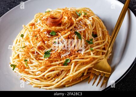 Pasta mollicata: Spaghetti mit Sardellen und gerösteten Paniermehl, Parmesankäse und Petersilie - traditionelles süditalienisches Gericht, serviert auf einem Teller o Stockfoto