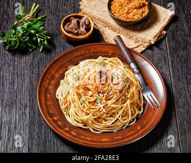 Pasta mollicata: Spaghetti mit Sardellen und gerösteten Paniermehl, Parmesankäse und Petersilie - traditionelles süditalienisches Gericht, serviert auf einem Teller o Stockfoto