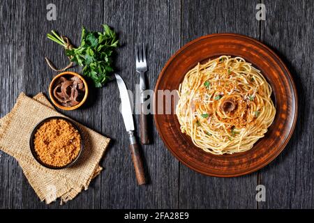 Pasta mollicata: Spaghetti mit Sardellen und gerösteten Paniermehl, Parmesankäse und Petersilie - traditionelles süditalienisches Gericht, serviert auf einem Teller o Stockfoto