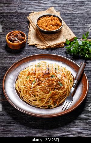 Pasta mollicata: Spaghetti mit Sardellen und gerösteten Paniermehl, Parmesankäse und Petersilie - traditionelles süditalienisches Gericht, serviert auf einem Teller o Stockfoto