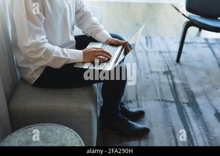 In der Hotellobby sitzt ein kaukasischer Geschäftsmann, der an der Arbeit arbeitet Notebook Stockfoto