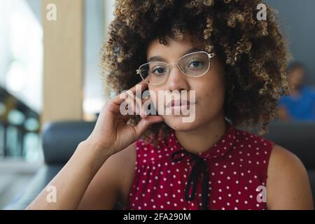 Porträt einer Geschäftsfrau mit gemischter Rasse, die eine Brille auf dem Sofa trägt Stockfoto