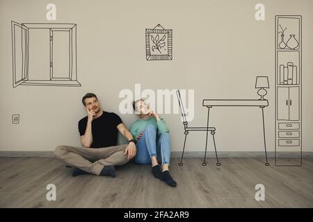Junges Paar stellen sich das Innere des neuen Hauses vor. Sitzen auf dem Boden und denken im leeren Raum Stockfoto