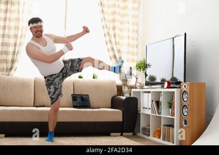 Der dicke Mann in Sportbekleidung und Kurzhanteln macht körperliche Bewegung Stockfoto