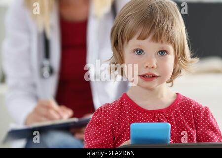 Porträt des kleinen Mädchens auf dem Hintergrund des Arztes in weißem Mantel. Stockfoto