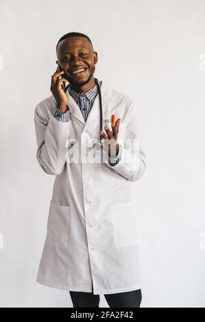 Schwarze Krankenschwester auf weißem Hintergrund spricht am Telefon Stockfoto