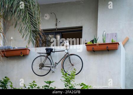 Tel Aviv, Israel - 17. April 2021: Ein rostiges Fahrrad mit einem Schädel darauf, das an einem Balkon in Tel Aviv, Israel, hängt. Stockfoto