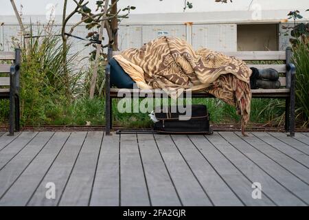 Tel Aviv, Israel - 17. April 2021: Eine Obdachlose, die in Tel Aviv, Israel, auf einer Bank schläft. Stockfoto