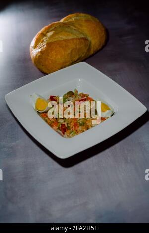 Portion gebratenen Reis mit Huhn, Gemüse und zwei Stücken gekochtem Ei mit frischem Brot serviert Stockfoto