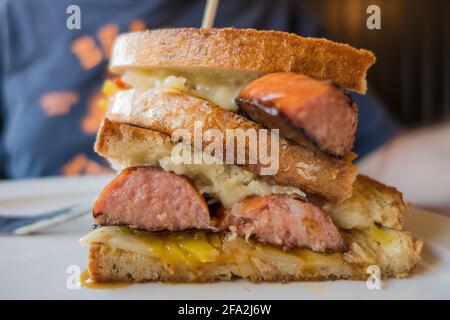 Köstliches gegrilltes Sandwich mit Wurst, Käse und Sauerkraut. Stockfoto