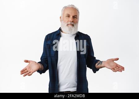Weiß nicht. Ahnungsloser älterer Mann mit Tattoos, zuckenden Schultern und verwirrtem Aussehen, verwirrt oder unbewusst, keine Ahnung haben, nicht verstehen Stockfoto