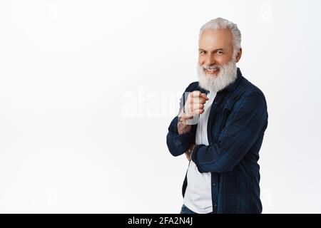 Wir brauchen Sie. Lächelnder, gutaussehender älterer Mann mit langem Bart, zeigt mit dem Finger auf die Kamera und sieht glücklich aus, wählt, lädt ein oder rekrutiert Menschen Stockfoto