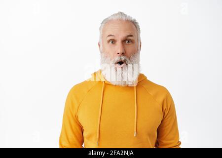 Nahaufnahme von beeindrucktem Senior-Hipster, der keucht, Wow sagt, bärtiger alter Mann lässt den Kiefer fallen und starrt vor Ehrfurcht auf die Kamera, schaut sich die tolle Werbung an Stockfoto