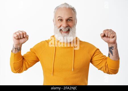Glücklich reifen Kerl mit Bart und Tattoos feiern Erfolg und Sieg, klatschen Fäuste und schütteln sie im Triumph, Ziel erreichen, gewinnen und lächeln Stockfoto
