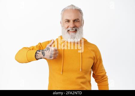 Sehr gut, gute Arbeit. Lächelnder Hipster alter Mann zeigt Daumen hoch mit seiner tätowierten Hand, genehmigen und mögen etwas, loben hervorragende Arbeit, machen Stockfoto