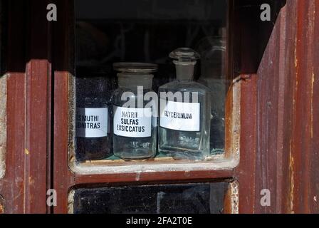 Glasflaschen auf einem schmutzigen Fenster einer alten Drogerie Stockfoto