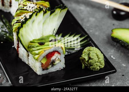 Sushi-Rolle mit grünem Drachen, Aal, Avocado, Gurke und Ingwer, begleitet von gebratenen Tempura-Garnelen. Traditionelle asiatische Reis Sushi gesunde Meeresfrüchte Stockfoto